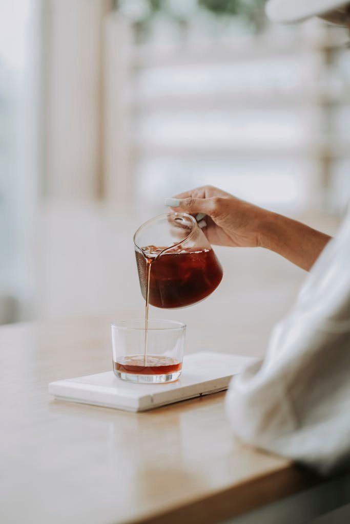 Aesthetic shot of fresh coffee being poured into glass on a wooden counter in Bali.